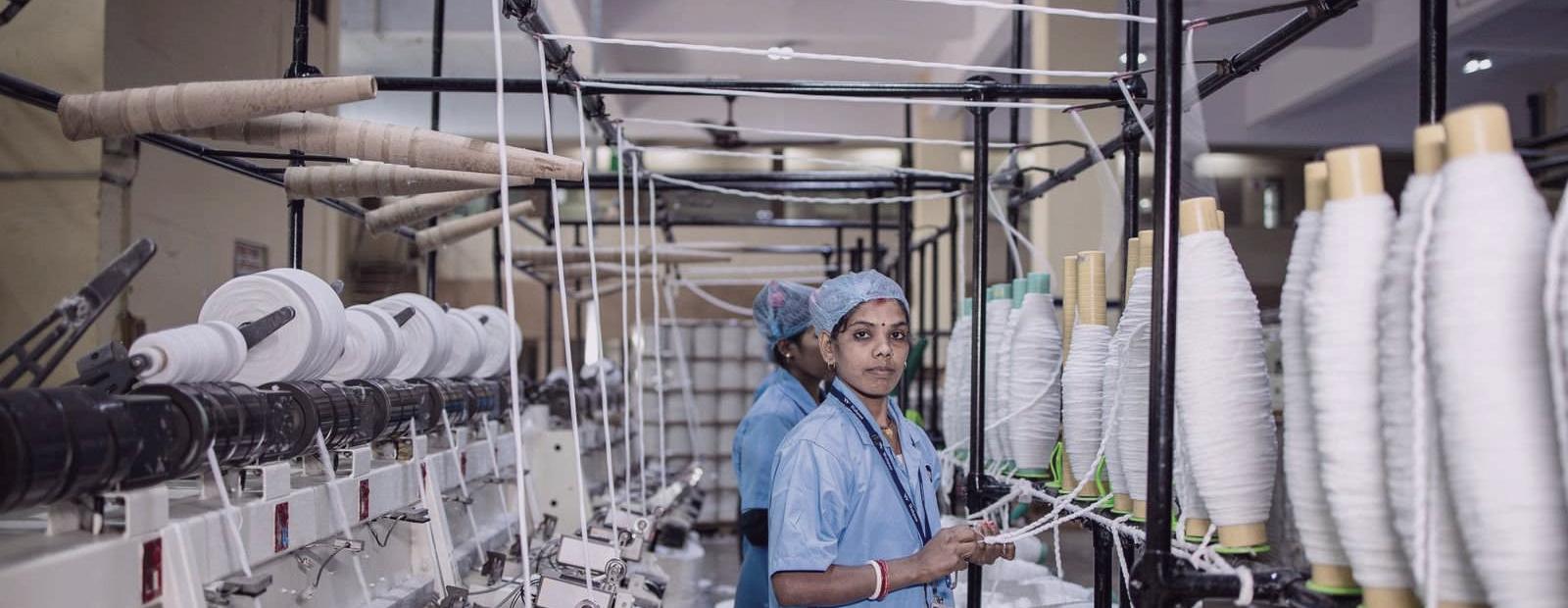 Workers in uniform at spinning machines in an Indian textile mill