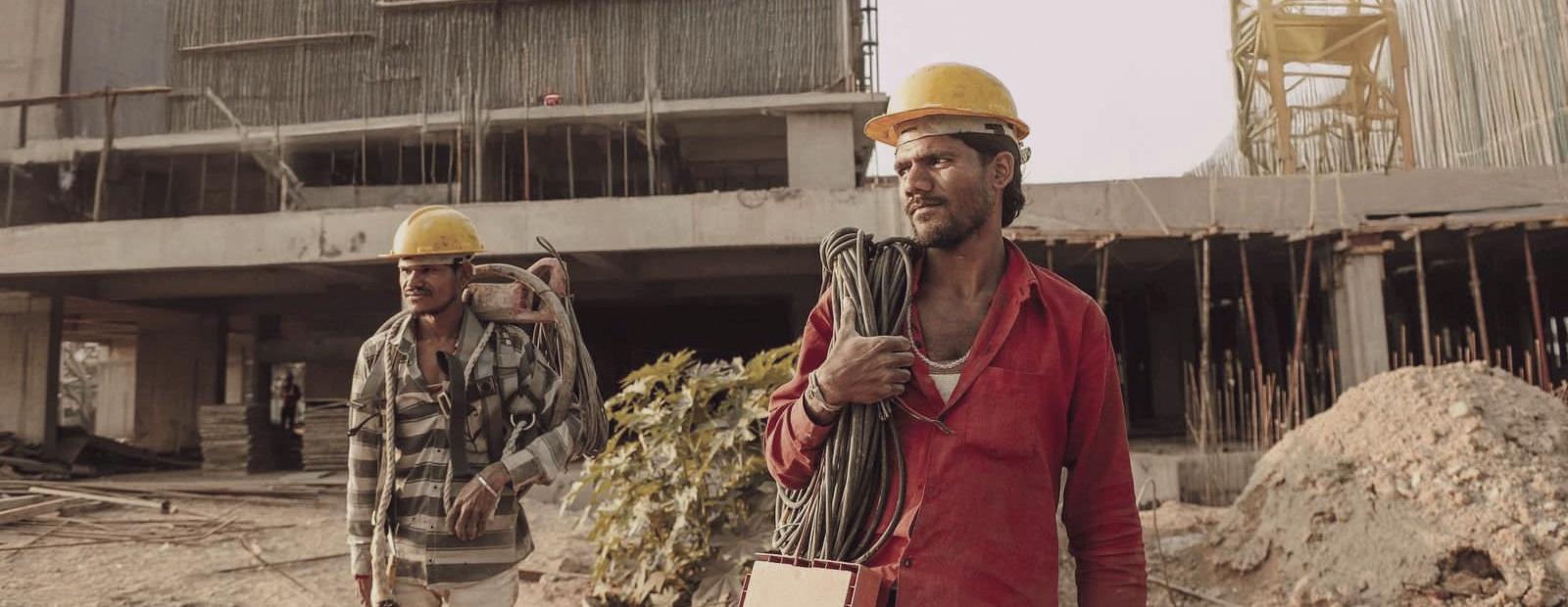 Two construction workers in safety helmets at a building site in India